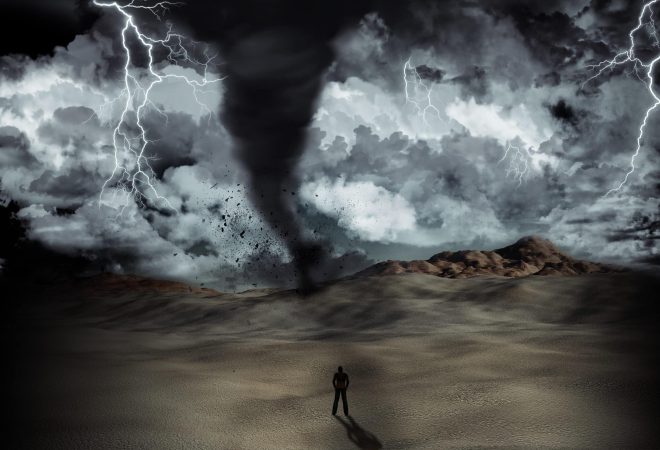 Silhouette of a man stood in the desert in the middle of a storm with tornado and lightning