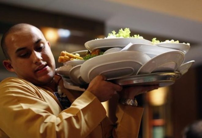 Garçom carrega bandeja de pratos em restaurante de Porto Alegre, Rio Grande do Sul