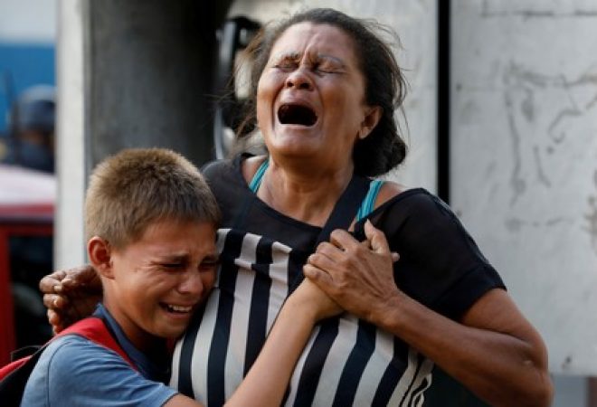 Familiares de presidiários do quartel-general da polícia do Estado de Carabobo, na Venezuela, reagem do lado de fora da prisão após incêndio