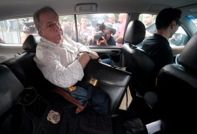 Antonio Celso Grecco, dono da Rodrimar, companhia que opera alguns serviços no porto de Santos, é escoltado por um agente da Polícia Federal na sede da PF em São Paulo, no Brasil