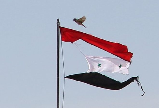 Bandeira rasgada da Síria é vista na cidade de Qamishli