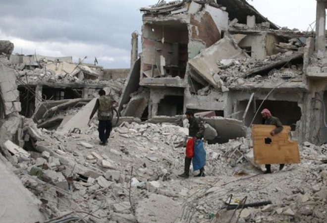 Pessoas caminham sobre destroços de prédios em Douma