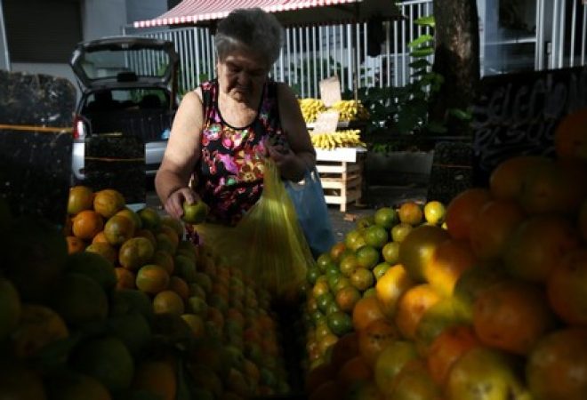 Consumidora compra laranjas em feira no Rio de Janeiro