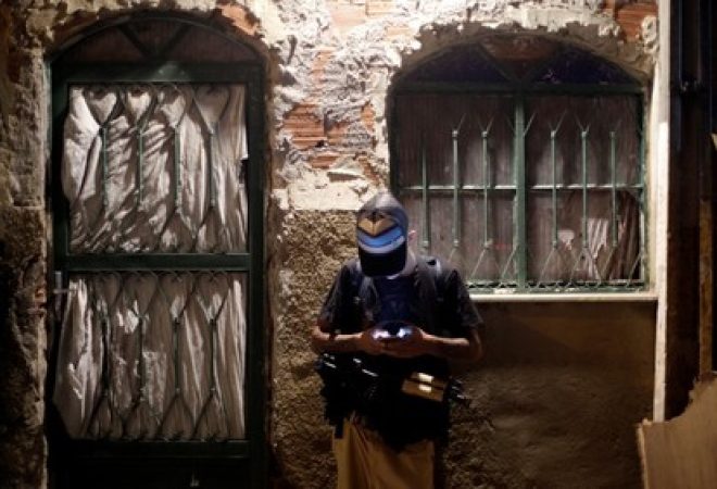 Integrante de facção olha celular em favela do Rio de Janeiro