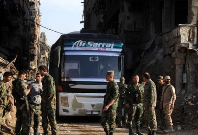 Soldados leais ao presidente sírio, Bashar al-Assad, perto de ônibus transportando rebeldes do campo de Yarmouk