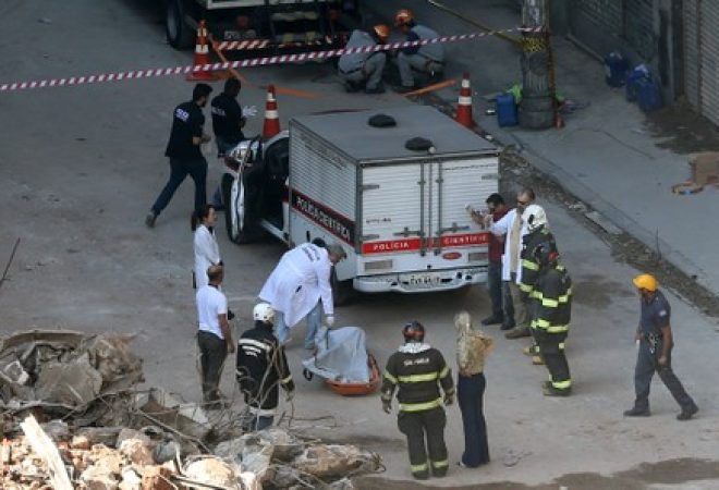 Polícia forense examina corpo de vítima achado nos escombros do prédio que desabou na madrugada de terça-feira, São Paulo, Brasil