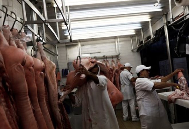 Funcionário carrega pedaço de carne em açougue em São Paulo