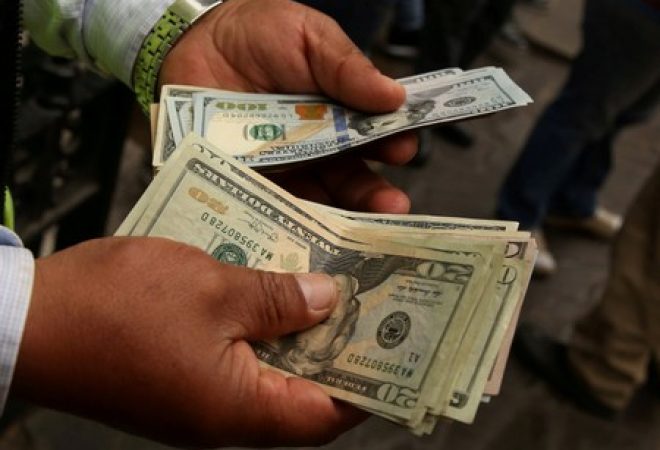 Homem manuseia notas de dólar