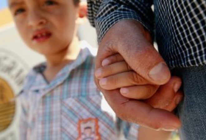Migrante de El Salvador Epigmenio Centeno segura mão do filho após ter desistido de tentar entrar nos EUA