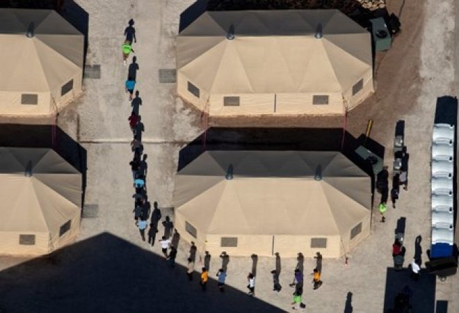 Crianças imigrantes são acompanhadas por funcionários em centro de detenção na fronteira dos Estados Unidos com o México