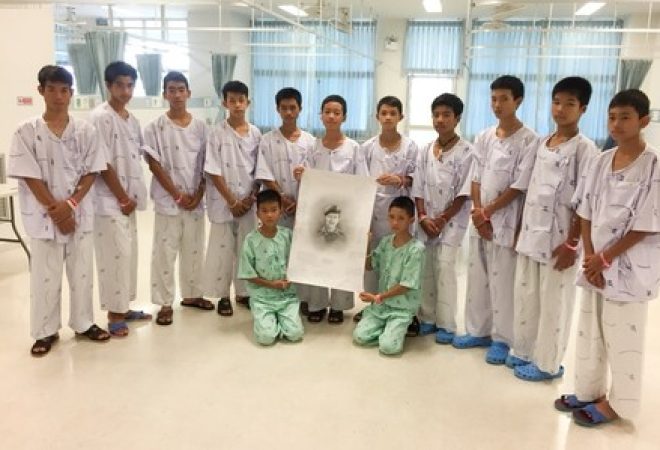 Meninos de time tailandês e seu técnico posam com desenho de mergulhador que morreu durante operação de resgate em caverna inundada