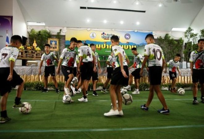 Meninos do time Javalis Selvagens e seu técnico jogam bola antes de entrevista coletiva em Chiang Rai