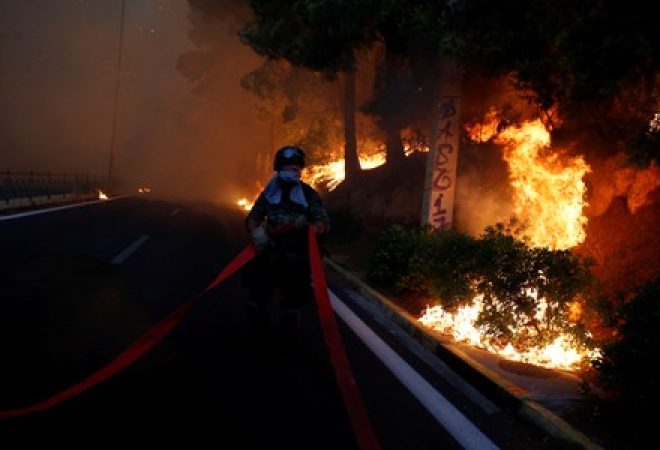 Soldado diante de incêndio na cidade de Rafina, perto de Atenas