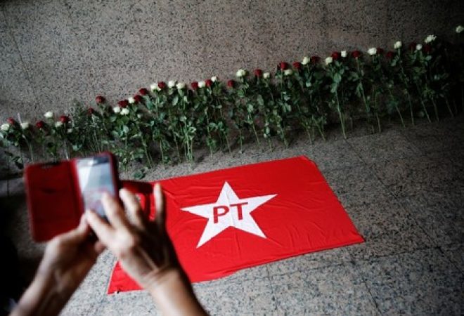 Mulher tira foto de bandeira do PT ao lado de flores em São Paulo