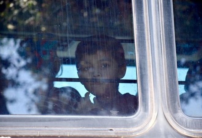 Criança dentro de ônibus com imigrantes perto de centro de detenção no Texas