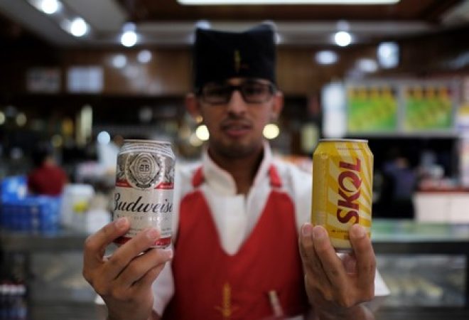Garçom posa segurando latas de cerveja dentro de um bar em São Paulo