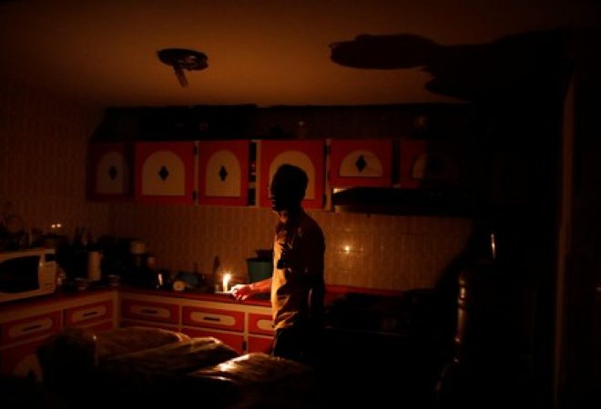 Américo Fernández usa vela para iluminar cozinha de sua casa durante apagão em Maracaibo, na Venezuela