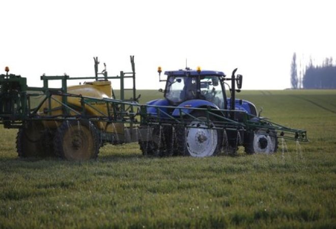 Trator pulveriza pesticida em plantação