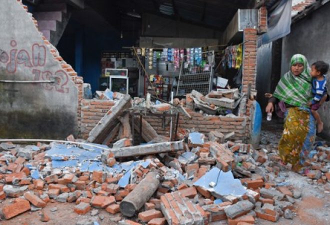 Mulher passa por destroços de parede destruída por forte terremoto em Lombok, na Indonésia