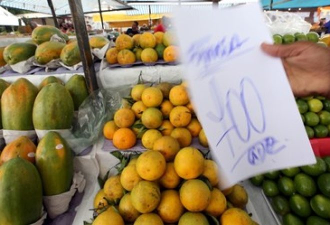 Vendedor segura placa com preço de fruta em feira de São Paulo