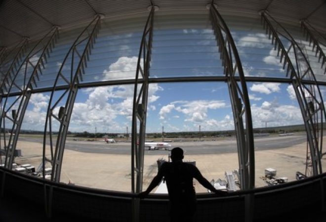 Homem olha para fora de uma área do Aeroporto Internacional de Brasília Presidente Kubitschek