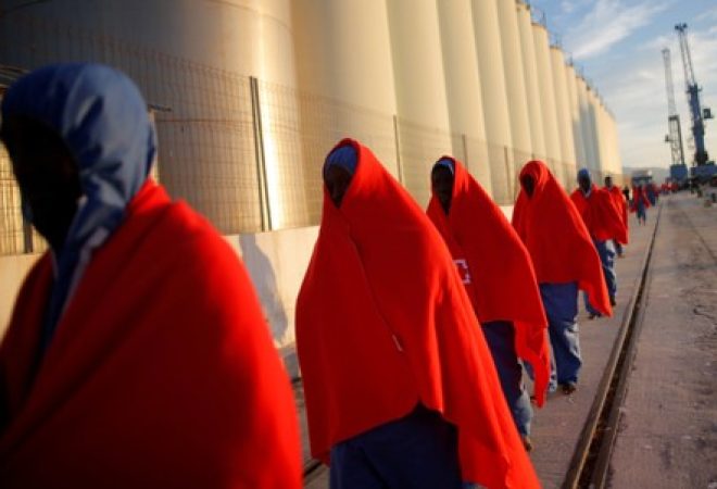 Imigrantes caminham no porto de Málaga após desembarcarem de navio de resgate