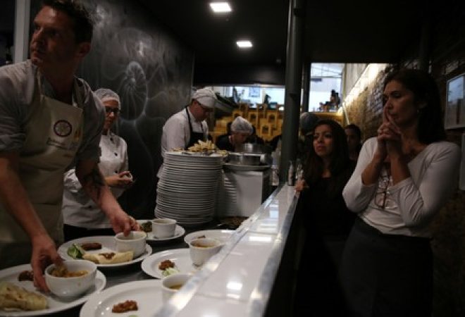 Cozinheiros finalizam pratos em foto ilustrativa