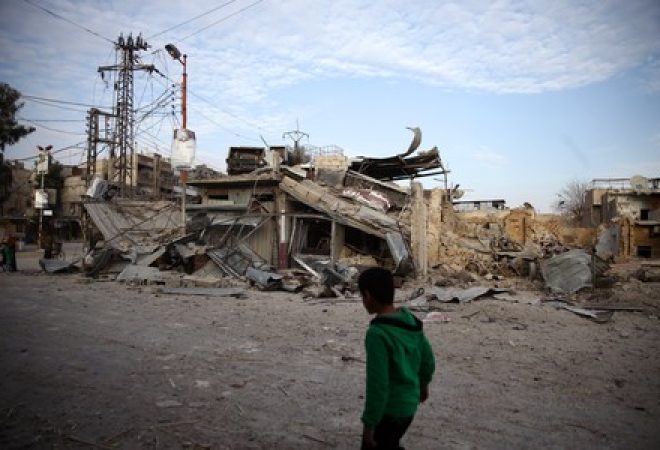 Criança passa por prédios destruídos na cidade de Douma, em Ghouta Oriental, na Síria