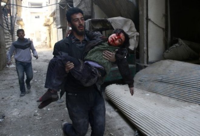Homem carrega garoto ferido na cidade de Hamouriyeh, na região síria de Ghouta Oriental