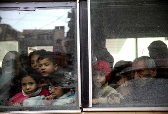 Crianças olham através de janela de ônibus enquanto deixam cidade de Douma, em Ghouta Oriental, na Síria