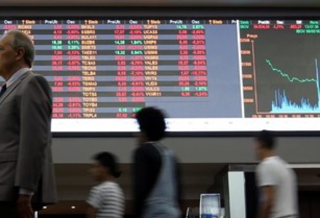 Pessoas passam por gráfico de flutuações do mercado na Bovespa, no centro de São Paulo, Brasil