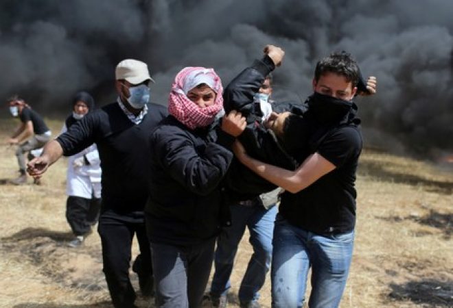 Palestino ferido é carregado durante confrontos com soldados israelenses na fronteira entre Israel e Gaza