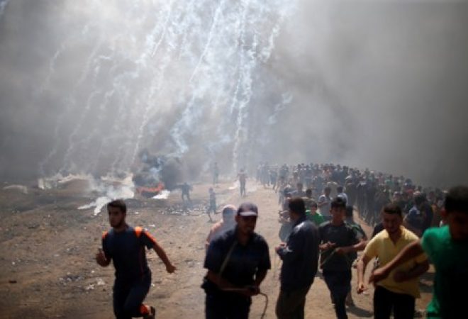Manifestantes palestinas correm de gás lacrimogêneo lançado por forças israelenses na fronteira entre Gaza e Israel