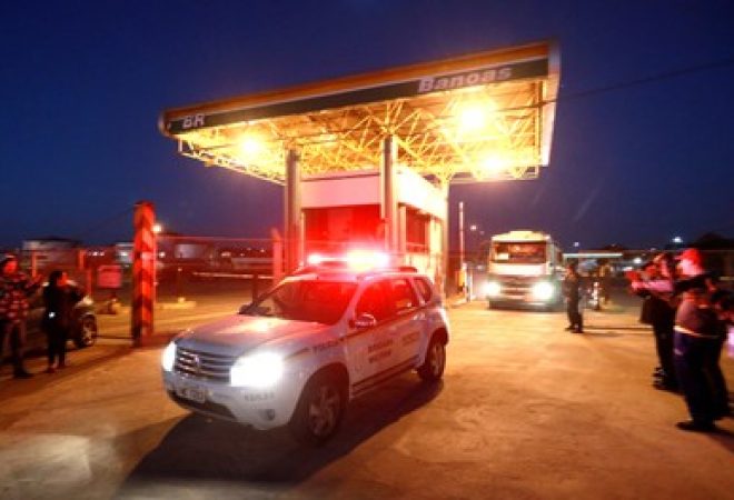 Carro de polícia escolta caminhões-tanque em posto de gasolina de Canoas, no Rio Grande do Sul