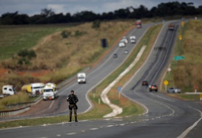 Army officers escort trucks transporting cooking gas and aviation gasoline to fuel airplanes at International Brasilia Airport, on the BR-040 highway in Luziania