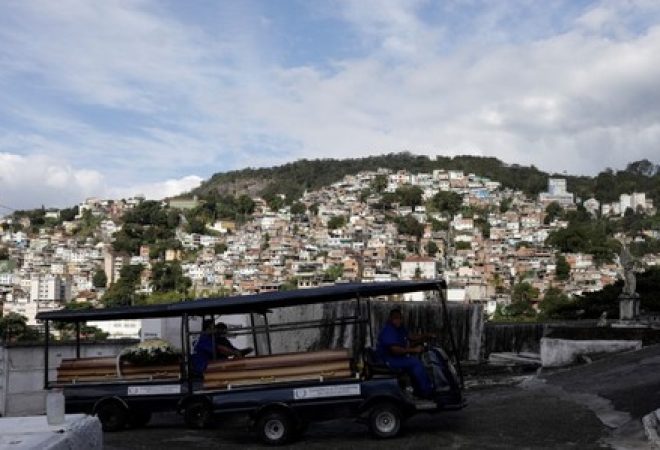 Funcionários de cemitério do Rio de Janeiro transportam caixões de duas mulheres mortas durante confronto entre policiais e traficantes na favela da Mangueira