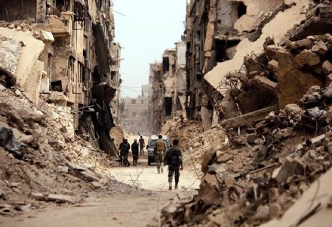 Soldados passam por prédios destruídos em Damasco