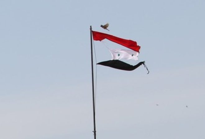 Bandeira rasgada da Síria é vista na cidade de Qamishli