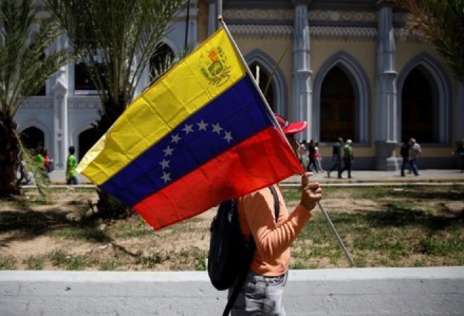 Venezuelano segura bandeira da Venezuela durante protesto em Caracas