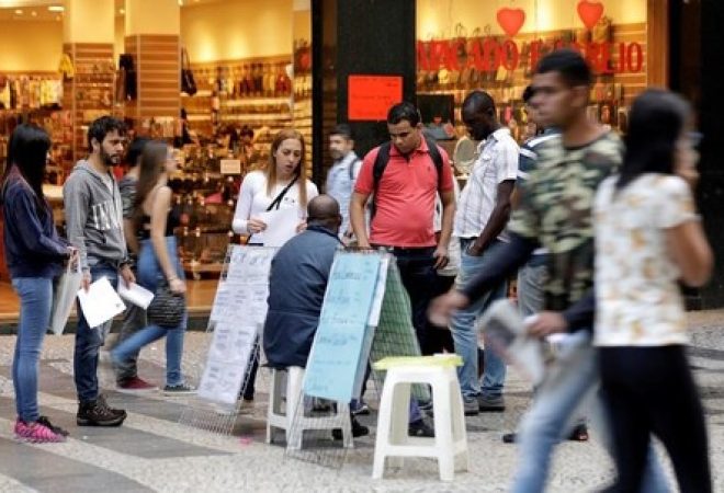 Pessoas olham para listas de vagas de emprego postadas em uma rua no centro de São Paulo, Brasil