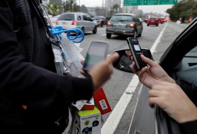 Vendedor ambulante recebe pagamento com cartão de crédito de um motorista durante a hora do rush em uma das principais vias de São Paulo