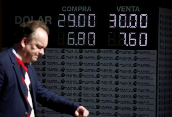 Homem passa por paínel eletrônico de cotação em Buenos Aires, Argentina