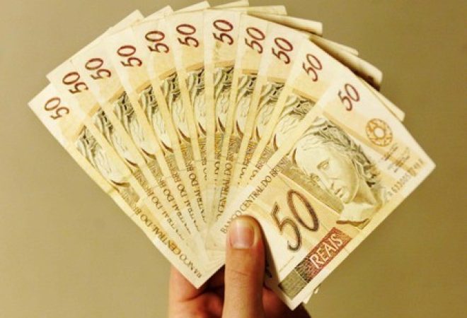 Pessoa segura notas de reais