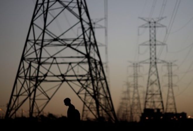 Homem passa por torres de energia em Brasília, Brasil