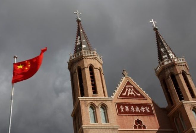 Bandeira da China ao lado de igreja católica em vilarejo de Huangtuang