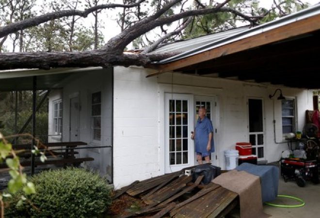 Andrew Lamonica observa árvore que caiu sobre sua casa durante passagem do furacão Michael, na Flórida, Estados Unidos