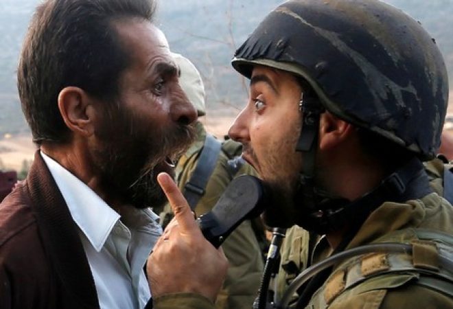 Palestino discute com soldado isralense durante confrontos devido a uma ordem de Israel para fechar uma escola palestina na Cisjordânia ocupada