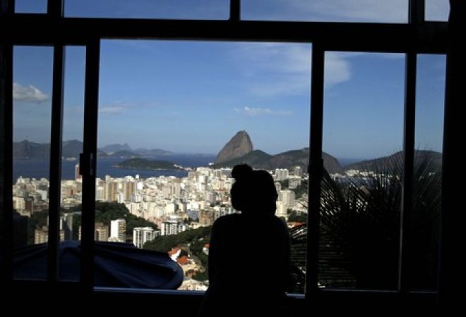 French student Melodie Valerio looks out the window of her rented room in the Pereira da Silva slum in Rio de Janeiro