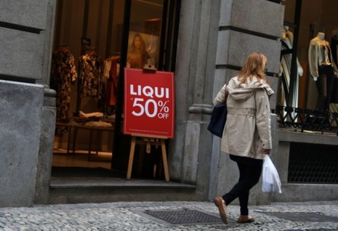 Mulher passa por vitrine de loja de roupas no centro do Rio de Janeiro
