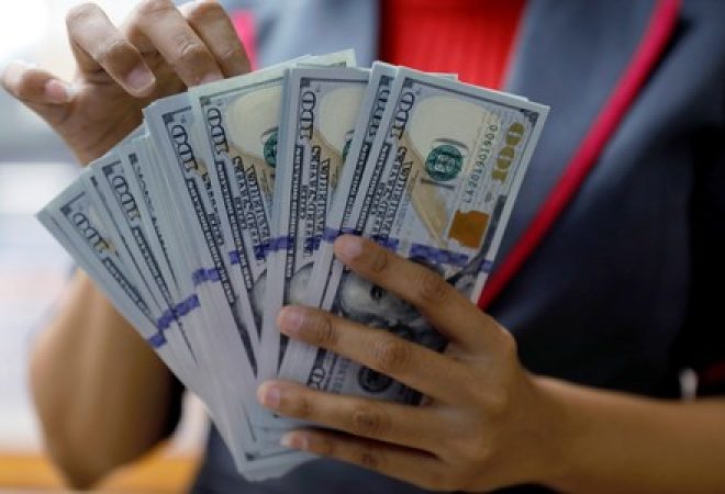 An employee counts U.S. dollar banknotes at a currency exchange office in Jakarta